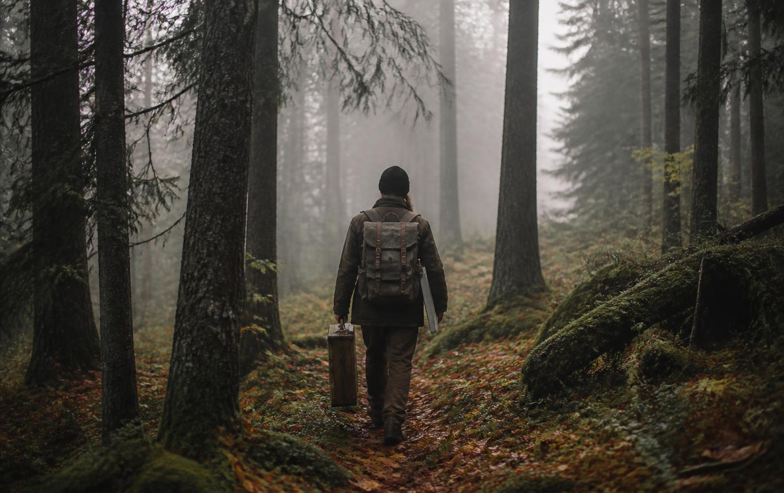 The painter walking into a misty forest with a wooden paint box